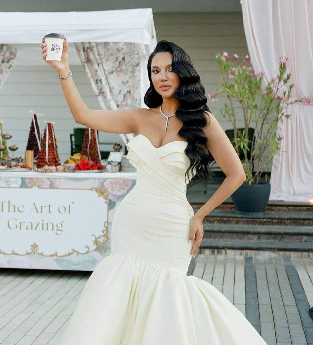 Mireasă ținând o cană Extra Shot, lângă un bufet elegant de nuntă